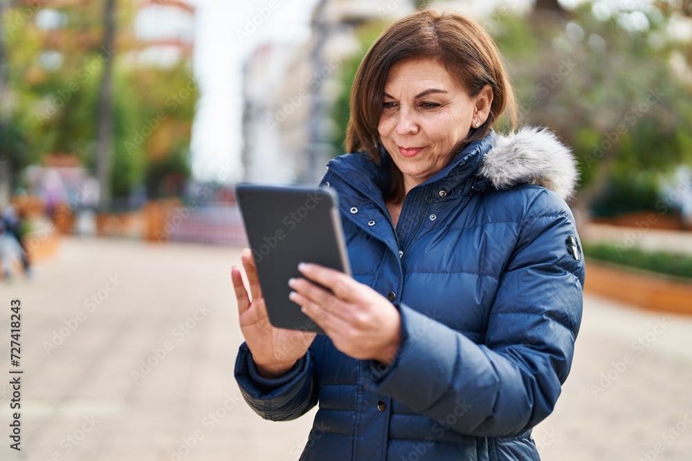 Obraz premium Middle age woman smiling confident using touchpad at park