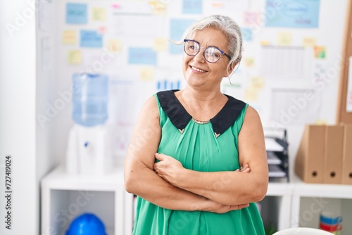 Middle age grey-haired woman business worker smiling confident standing with arms crossed gesture at office