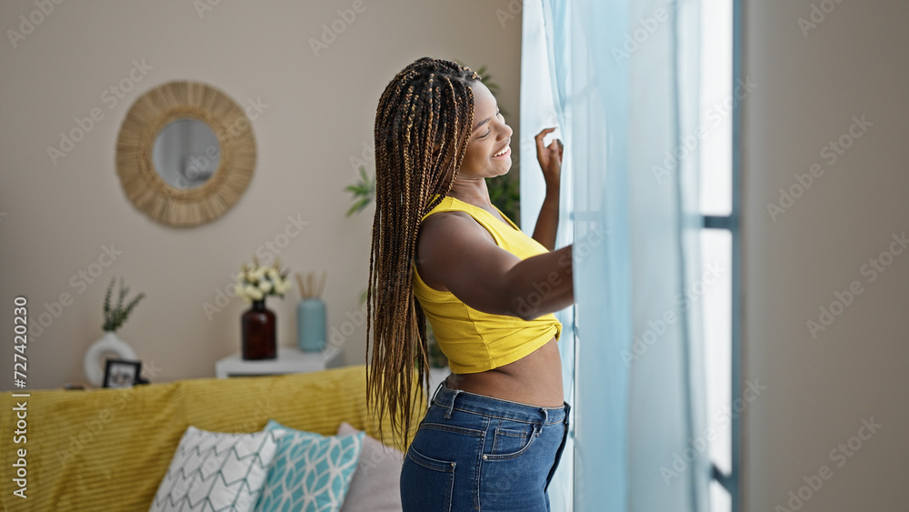 Fototapeta premium African american woman looking throw the window smiling at home