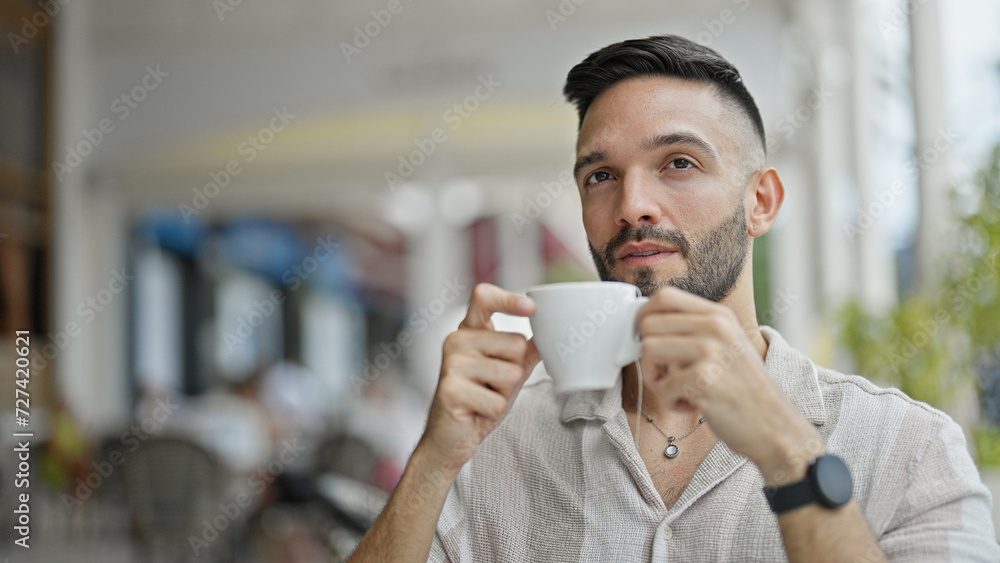 Young hispanic man holding cup of coffee at coffee shop terrace Young hispanic man holding cup of coffee at coffee shop terrace