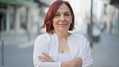 Middle age woman smiling confident standing with arms crossed gesture at street © Krakenimages.com