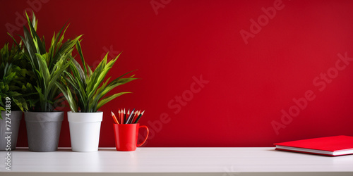 Workspace with red supplies, notebooks,plant and copy space. Home office desk.