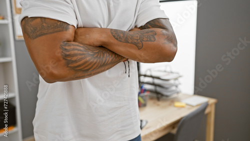 Confident african american man with tattoos crossed arms in a modern office setting