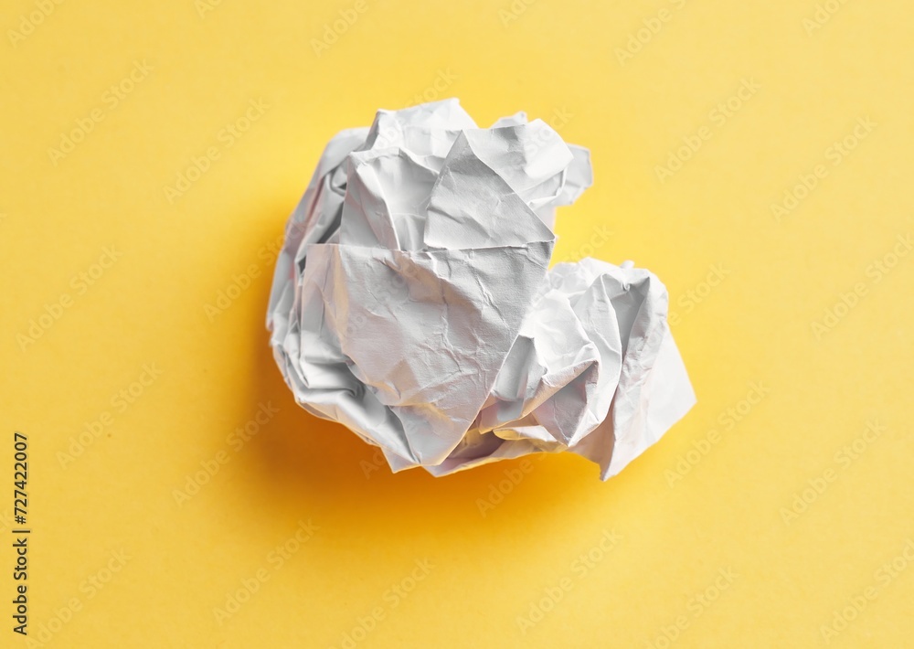  One white crumpled paper ball over isolated yellow background