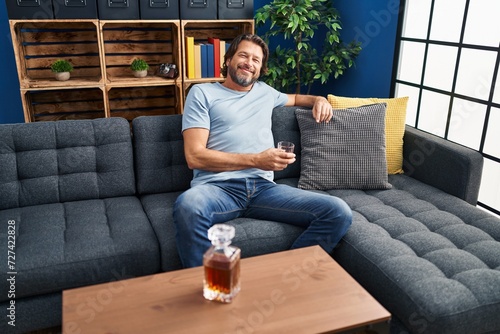 Middle age man drinking glass of whisky sitting on sofa at home © Krakenimages.com