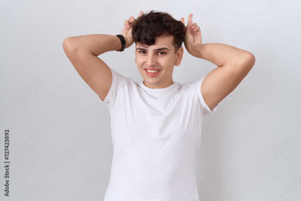 Young non binary man wearing casual white t shirt posing funny and crazy with fingers on head as bunny ears, smiling cheerful Young non binary man wearing casual white t shirt posing funny and crazy with fingers on head as bunny ears, smiling cheerful