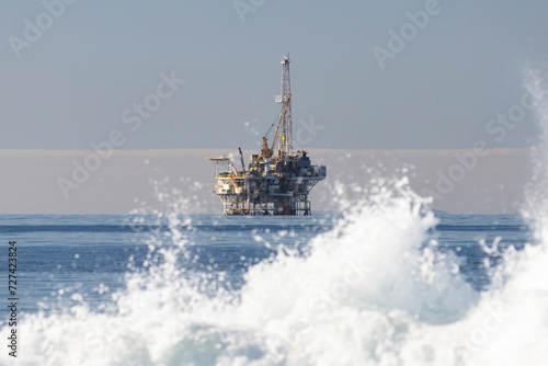 An Old Oil Rig In the Distance Beyond Crashing Waves