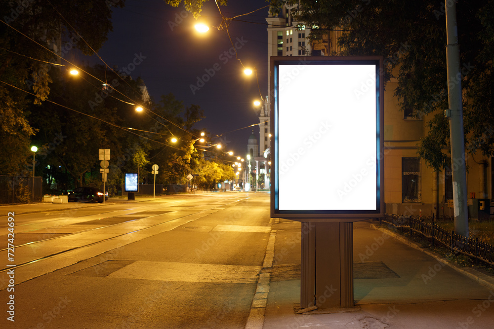 Vertical billboard advertising in the night city. Yellow street lighting with tram rails. Mock-up. Vertical billboard advertising in the night city. Yellow street lighting with tram rails. Mock-up.