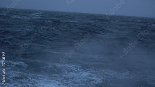 Storm. Sea. Splashes of waves fly by. View to waves low on water. Wind breaks waves with splashes. White foam on wind. Side view along ship.