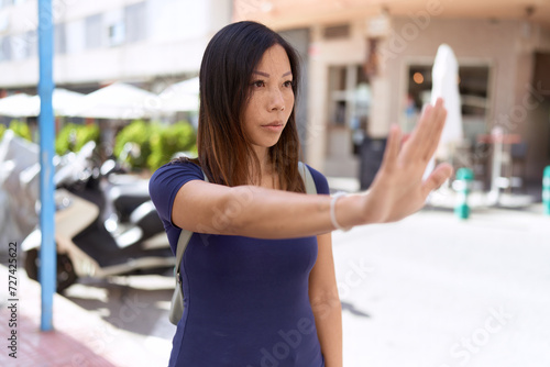Young asian woman doing stop gesture with hand at coffee shop terrace
