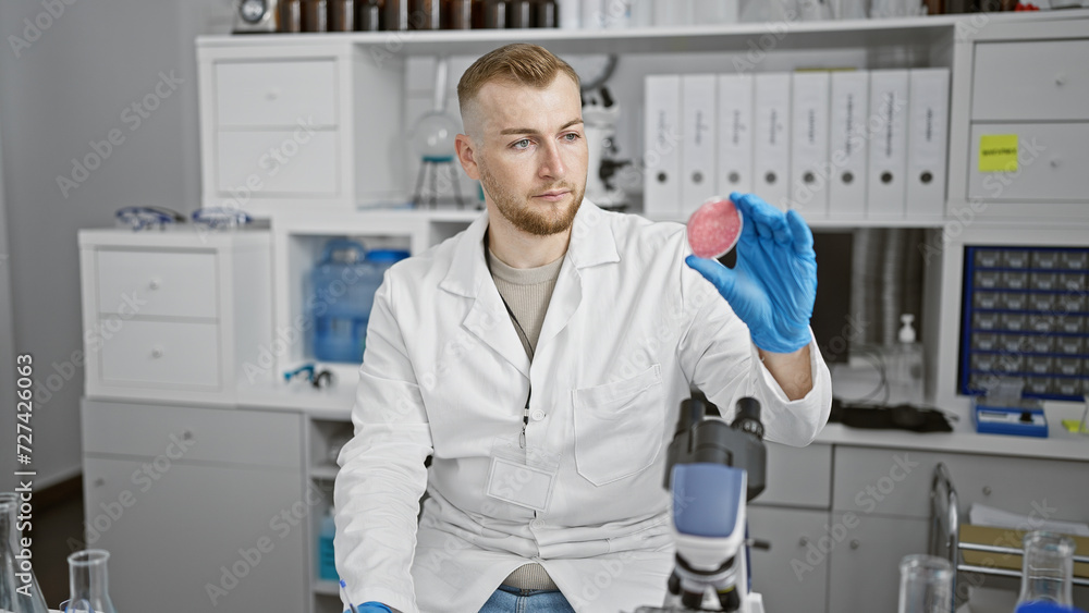 Attractive young man with a beard examines synthetic meat in a modern laboratory setting. Attractive young man with a beard examines synthetic meat in a modern laboratory setting.