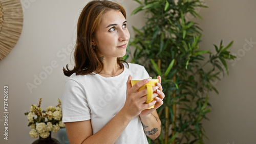 Young woman holding cup of coffee standing at home
