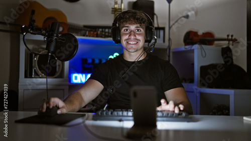 Attractive young hispanic man  a charismatic gamer  streaming overnight in his cozy gaming room playing a virtual game  smiling and engaging in conversation over video call.
