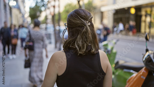 Beautiful hispanic woman in glasses striding away on madrid street, a view of urban elegance walking towards europe's heart
