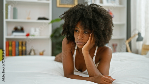 African american woman lying on bed looking sexy with serious face at bedroom