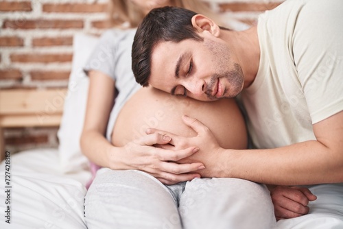 Man and woman couple listening baby sound sitting on bed at bedroom