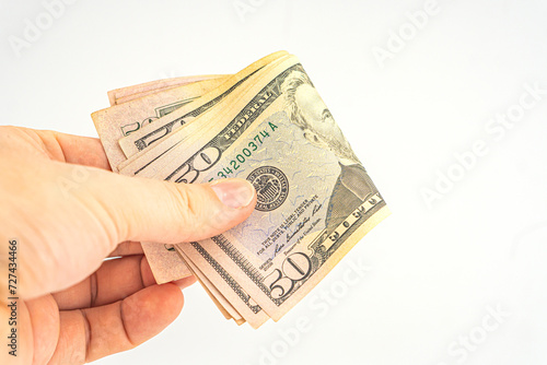 Man hand with dollars isolated on a white background. Businessman gives fifty dollars. Concept of tips and cash in America. A bundle of dollars, bribe, illegal traffic. Several 50 dollar bills in hand