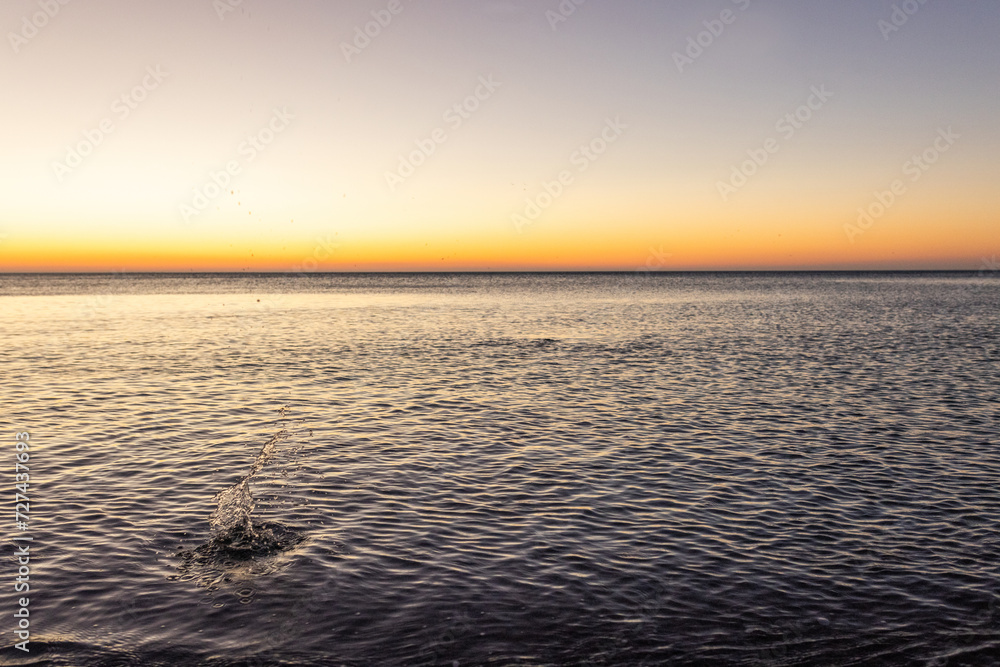 Obraz premium Sunrise on sea golden blue colors, Stones at sunset with blur, selective focus
