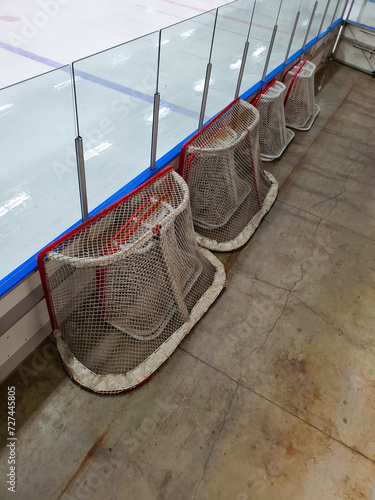 Hockey nets sitting at the side of a ice rink.
