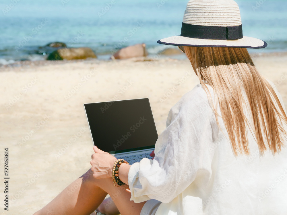 young woman uses laptop computer on the beach. distance work, freelancer and blogger concept. WiFi unlimited