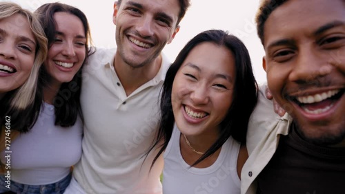 Multirracial group of young smiling friends looking at camera in the park hugging in community. Happy millennial people laughing taking selfie having fun together outside. Cheerful university students photo