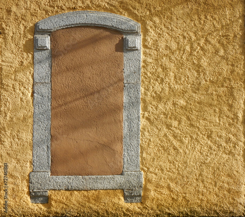Yellow wall with a closed and boarded window