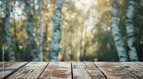 an empty wooden table on an outdoor wooden table with green birch trees on the background