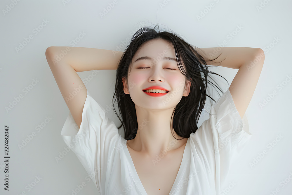 Fototapeta premium smiling asian woman with her arms raised above her head on white white background