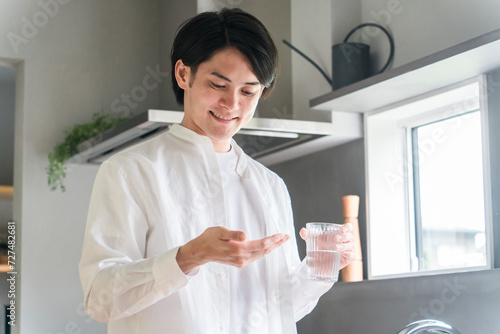 キッチンで内服薬・サプリ・医薬品を飲む病気の男性・投薬
 photo