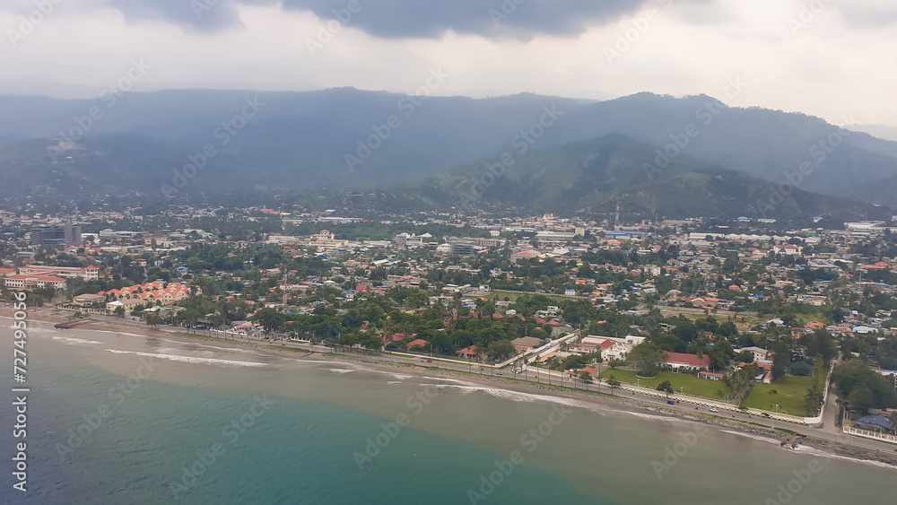 Scenic panoramic aerial view of the urban capital city of Dili with houses, buildings, ocean, beach and mountains in Timor-Leste, Southeast Asia 