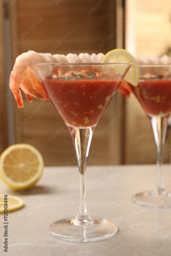 Tasty shrimp cocktail with sauce in glasses and lemon on light marble table