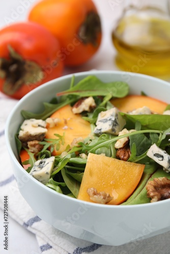 Tasty salad with persimmon, blue cheese and walnuts served on white table, closeup
