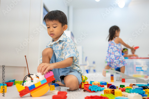 Adorable preschool asian kid boy and girl enjoying play colorful building toy block