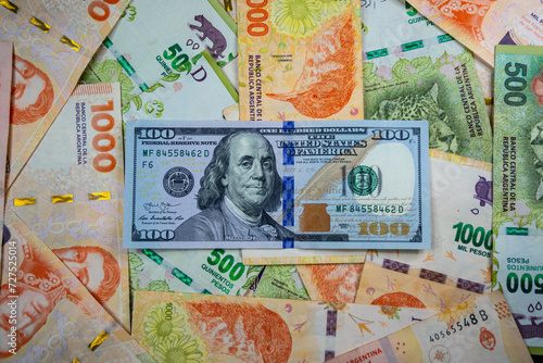 100 dollar note on a background of 1000 peso notes and 500 peso notes. USA and Argentina currencies. Monetary wallpaper. photo