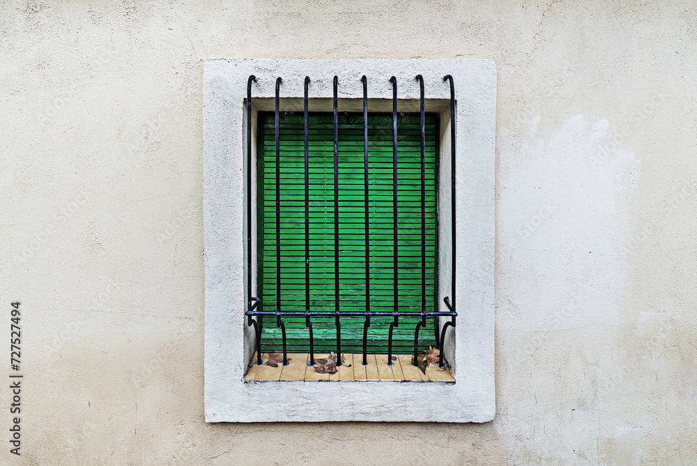 A wall of a building with a window with bars painted black