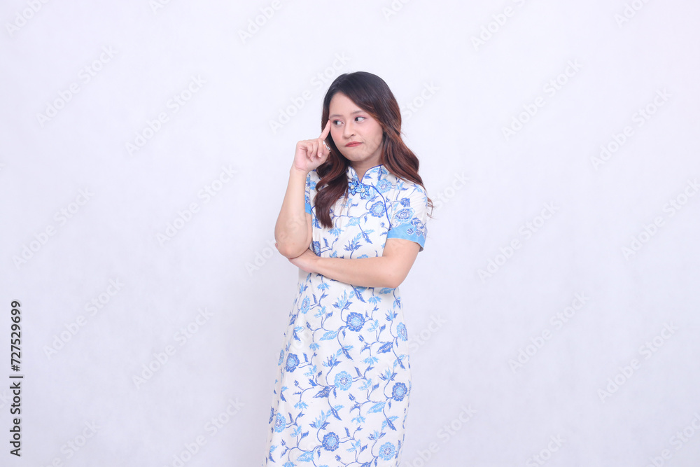 Beautiful serious asian woman wearing modern chinese dress arms crossed while thinking isolated on white background. happy Chinese New Year Beautiful serious asian woman wearing modern chinese dress arms crossed while thinking isolated on white background. happy Chinese New Year
