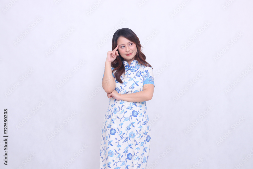 Beautiful Chinese Javanese woman with a graceful smile wearing a modern Chinese dress with her arms crossed and thinking on a white background. happy Chinese New Year Beautiful Chinese Javanese woman with a graceful smile wearing a modern Chinese dress with her arms crossed and thinking on a white background. happy Chinese New Year