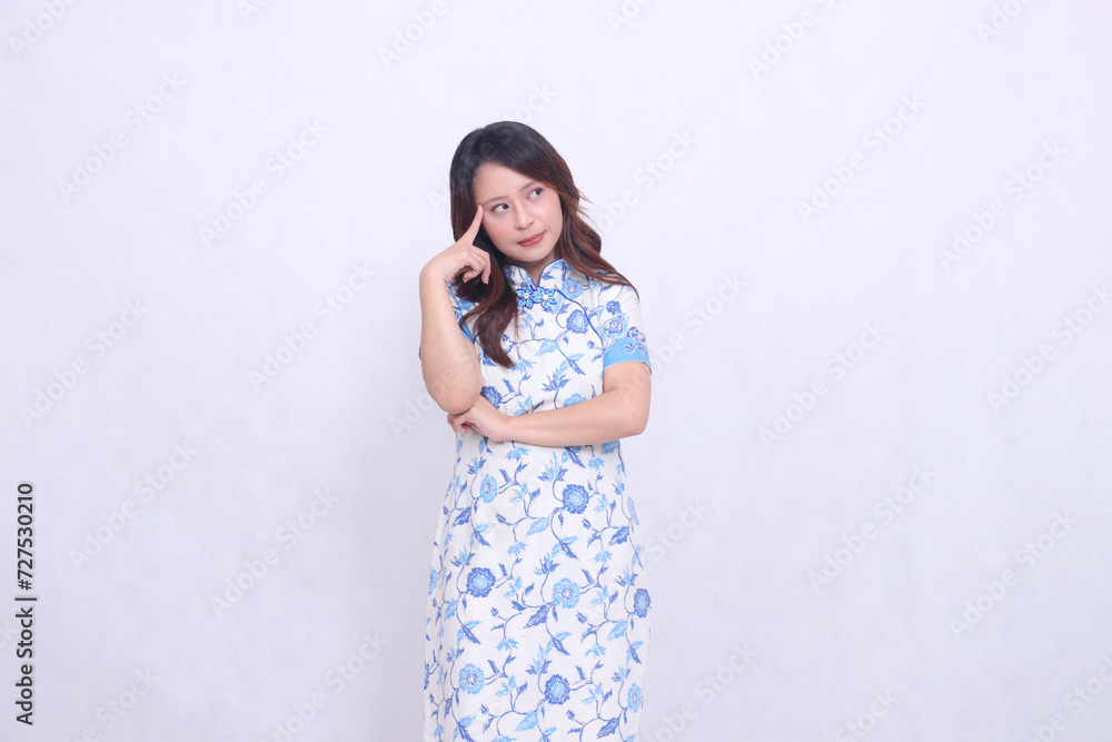 Beautiful Chinese Javanese woman with a flat smile wearing a modern Chinese dress, arms crossed, thinking on a white background. happy Chinese New Year Beautiful Chinese Javanese woman with a flat smile wearing a modern Chinese dress, arms crossed, thinking on a white background. happy Chinese New Year