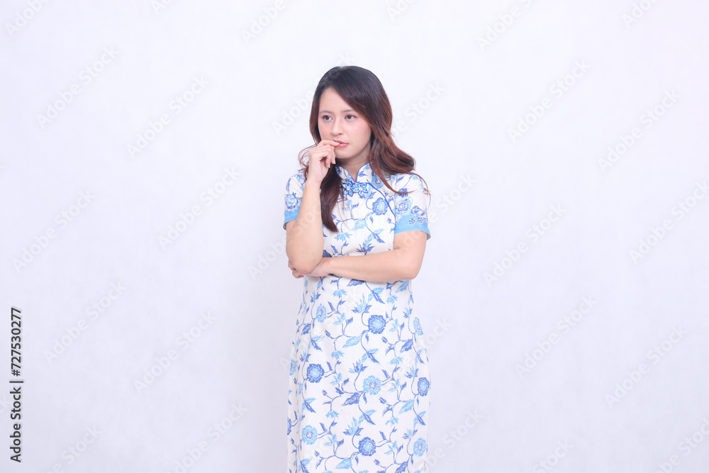 beautiful Javanese Chinese woman thinking wearing a modern Chinese dress with her arms crossed, left side view on a white background. happy Chinese New Year beautiful Javanese Chinese woman thinking wearing a modern Chinese dress with her arms crossed, left side view on a white background. happy Chinese New Year
