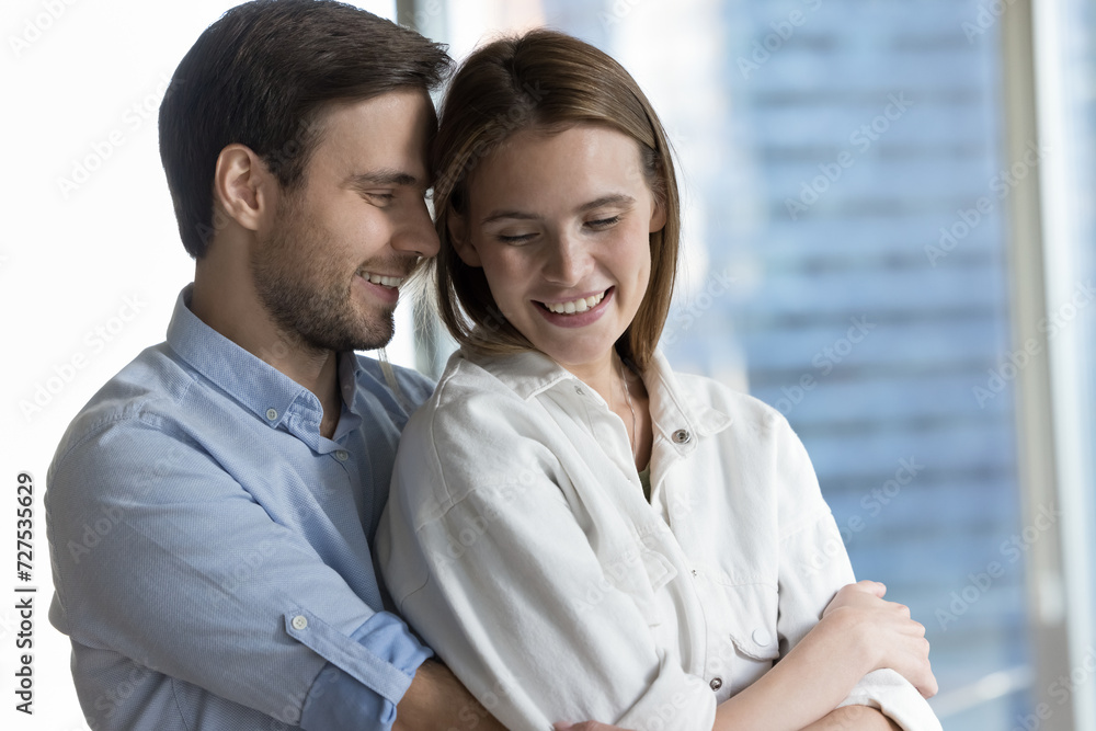 Close up beautiful loving couple hugging standing indoor. Young woman her beloved man embracing showing tender, feeling sincere love, enjoy harmonic relationships, happy marriage. Relations, romance