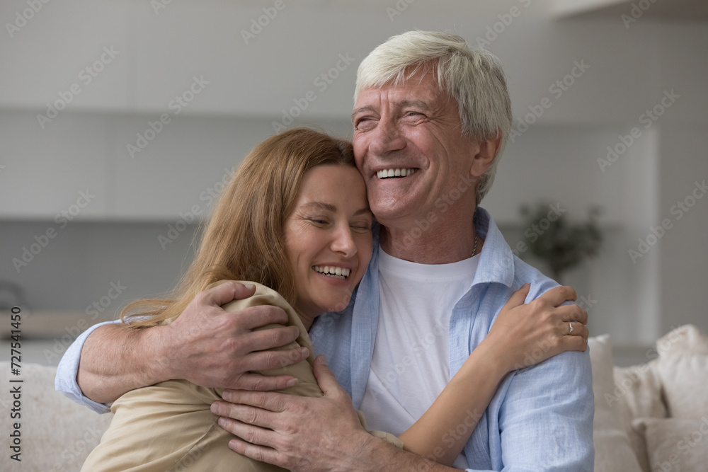 Cheerful loving old grey hair dad hugging adult daughter woman with love, care, warmth, enjoying meeting, fatherhood, family relationship, looking away, smiling, laughing Cheerful loving old grey hair dad hugging adult daughter woman with love, care, warmth, enjoying meeting, fatherhood, family relationship, looking away, smiling, laughing
