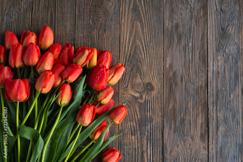 Fototapeta Naklejka Na Ścianę i Meble -  Fresh orange tulips on a wooden background. Springtime. Greeting card with copy space for Valentine's Day, Woman's Day and Mother's Day.