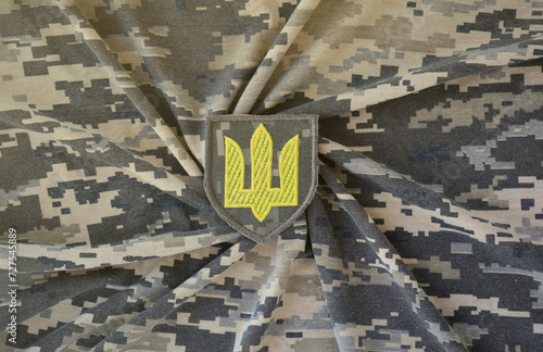 Symbol of Ukrainian army on the camouflage uniform of a Ukrainian soldier. The concept of war in Ukraine, patriotism and protecting your country from russian occupiers photo