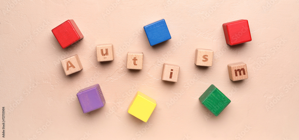 Word AUTISM with cubes on beige background