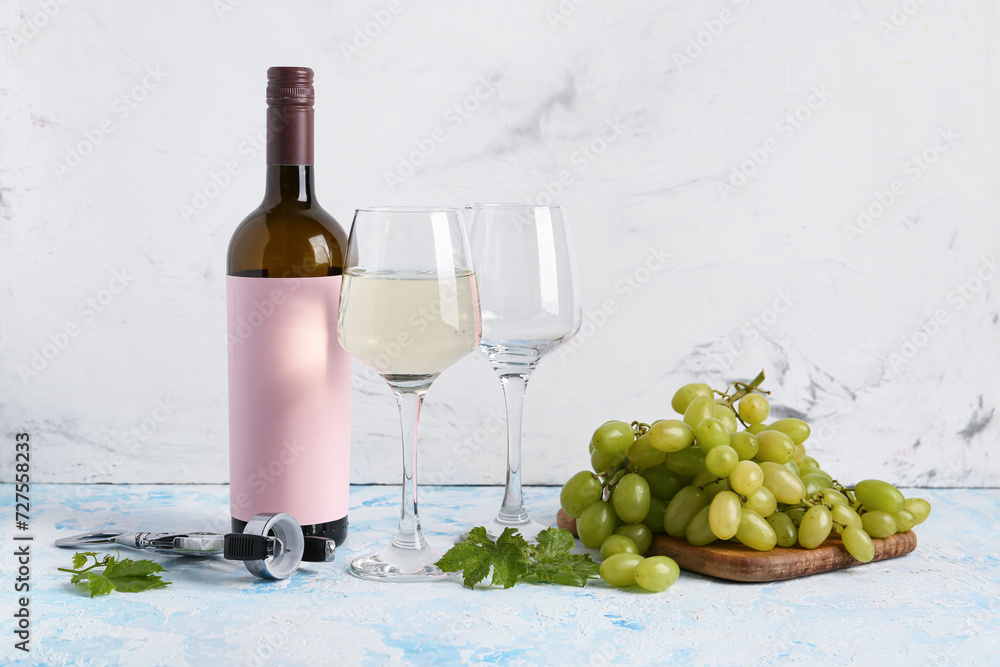 Fototapeta premium Bottle of wine with blank label and glasses on color background