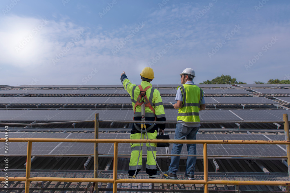 Naklejka premium workers at work. Couple worker discuss on solar rooftop. engineer work on sustainable solar cell on roof of factory.