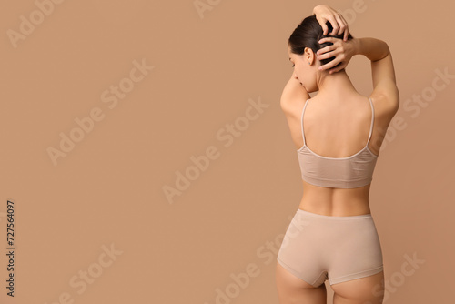 Beautiful young woman in underwear on beige background © Pixel-Shot