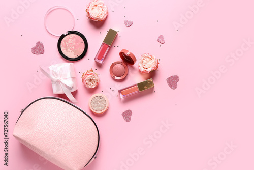 Cosmetic bag with makeup products, gift box and roses on pink background