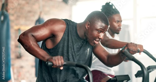 Fitness, cardio and black man on machine in gym for intense workout, training and exercise for healthy body. Sports, sweating and people on cycling equipment for performance, endurance and wellness photo