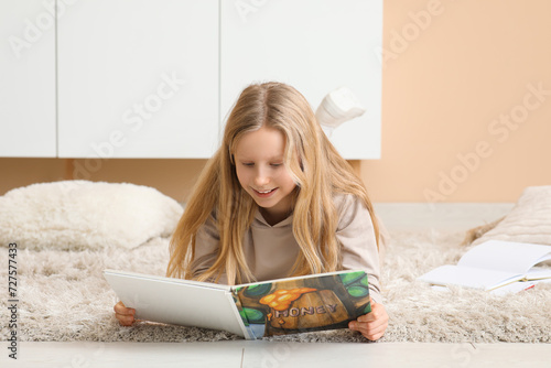 Smiling young girl reading ...